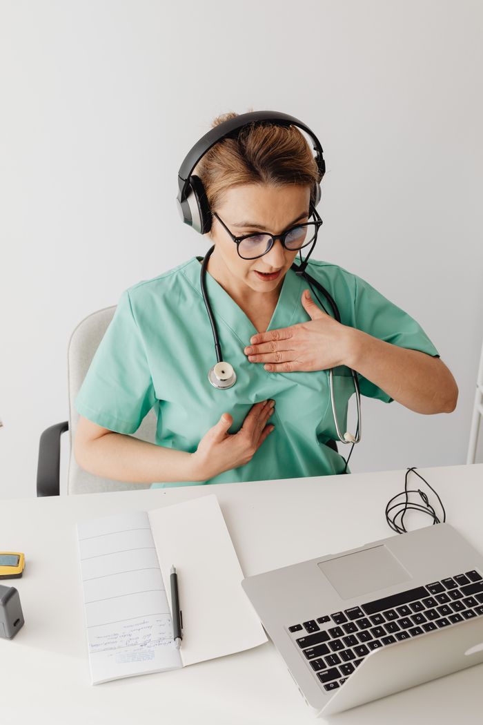 services-bg A female doctor in scrubs wearing headphones conducts an online consultation.